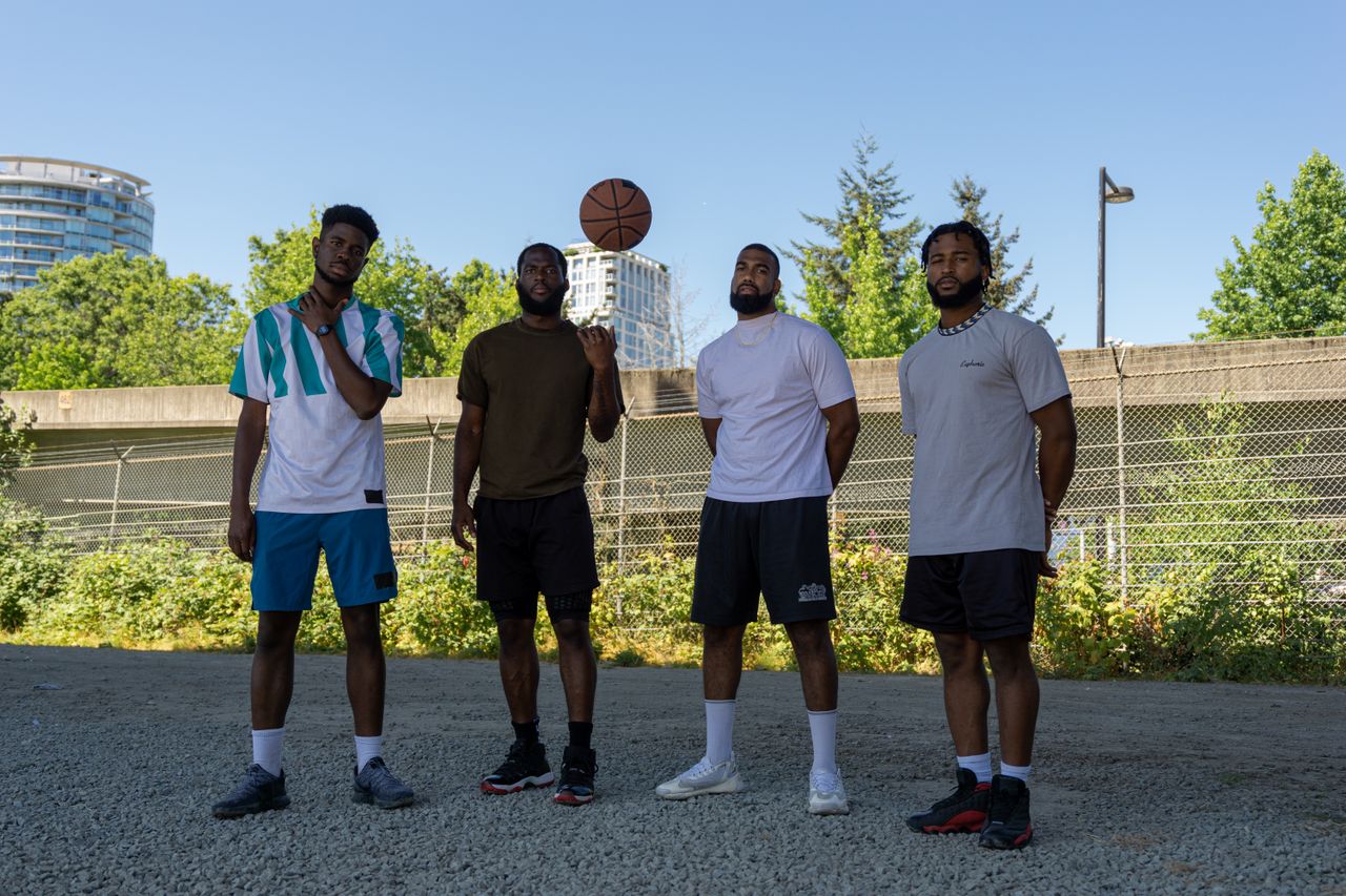 A group of men in activewear posing with a basketball outdoors.